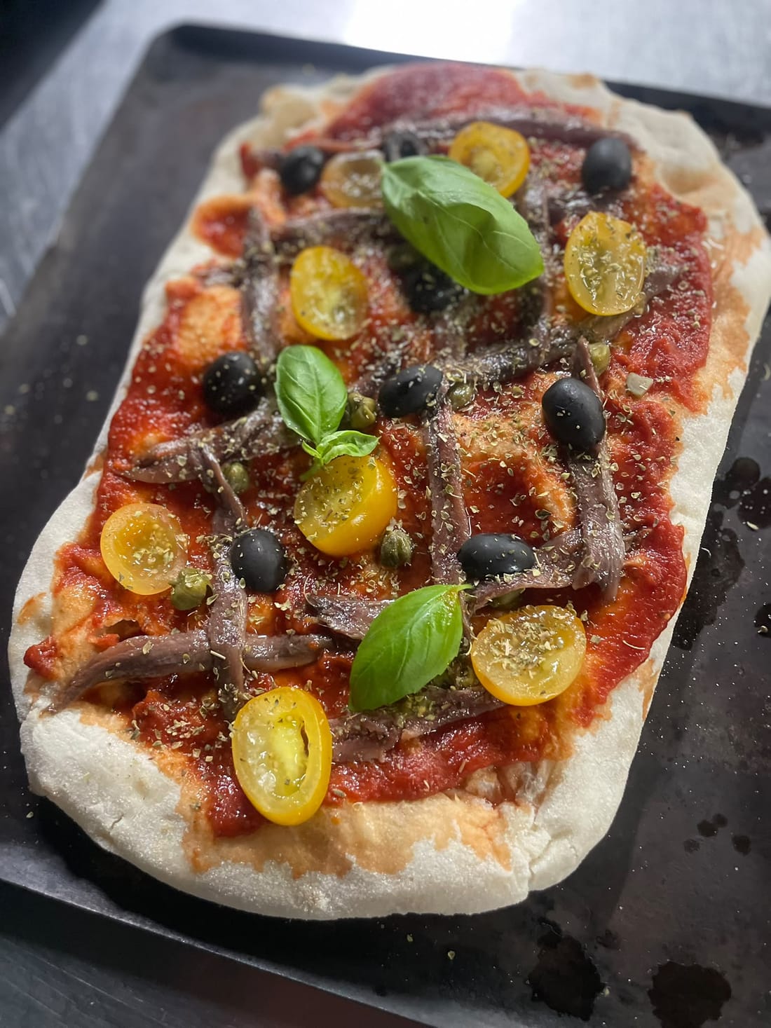 Pinsa La Mediterranéa — tomate, anchois, câpres, tomates cerises, basilic